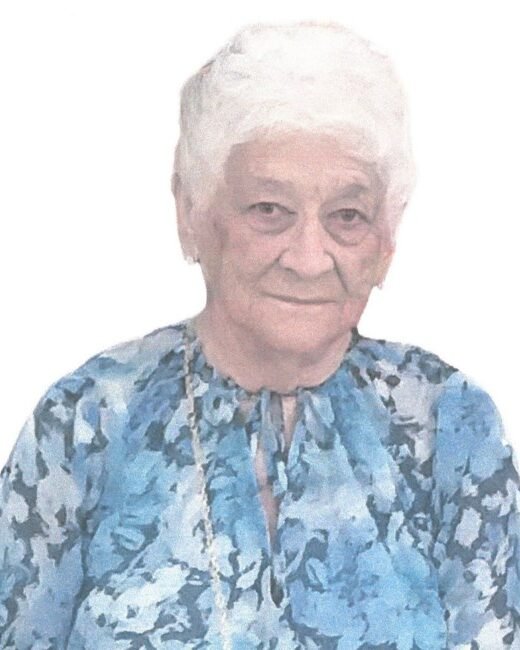 Elderly woman in blue floral blouse smiling softly.