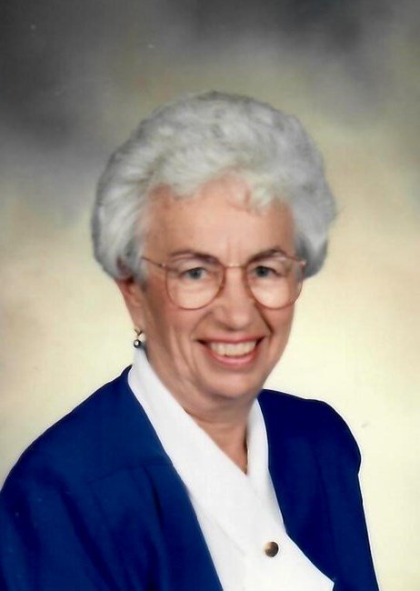Smiling elderly woman with glasses and white hair.
