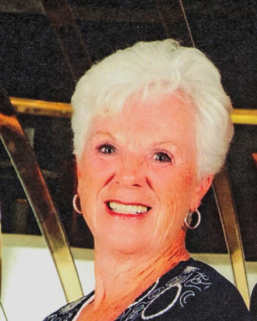 Smiling elderly woman with white hair and earrings.