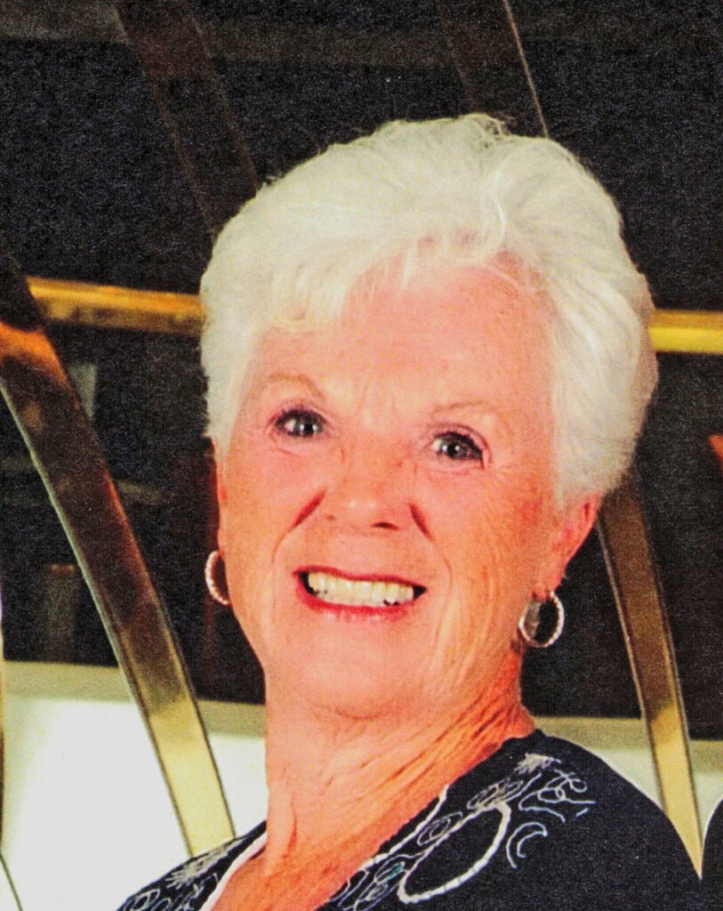 Smiling elderly woman with white hair and earrings.