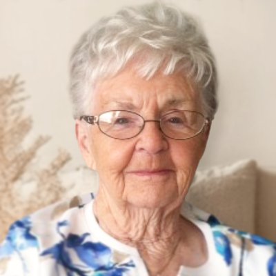 Elderly woman with glasses, short white hair smiling.