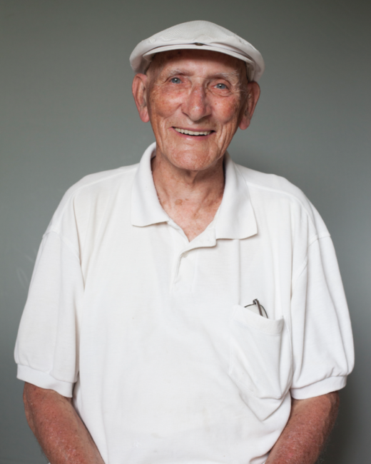 Smiling elderly man in white shirt and hat.
