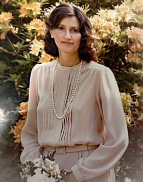 Woman in garden with flowers and pearls.