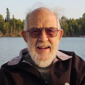 Elderly man smiling by a lake.