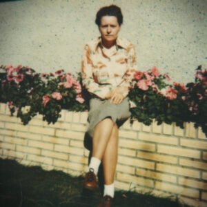 Person sitting on brick ledge with flowers