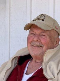 Smiling man wearing a beige cap and jacket.