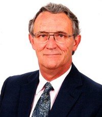 Elderly man in suit with glasses and tie.