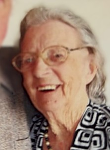 Smiling elderly woman with glasses and patterned shirt.