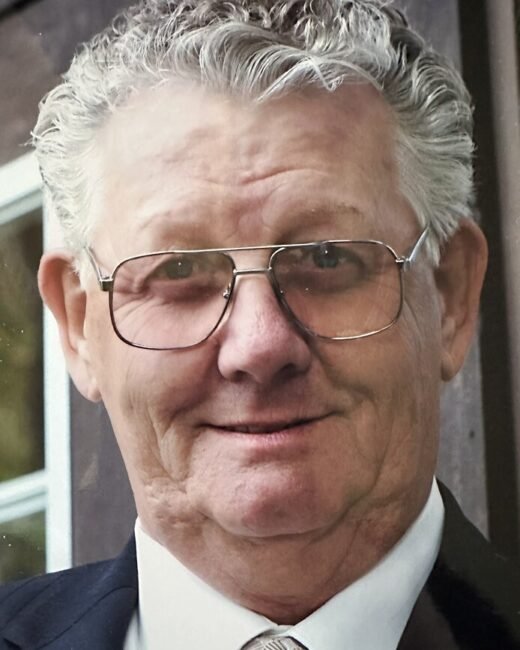Smiling elderly man with glasses and suit.