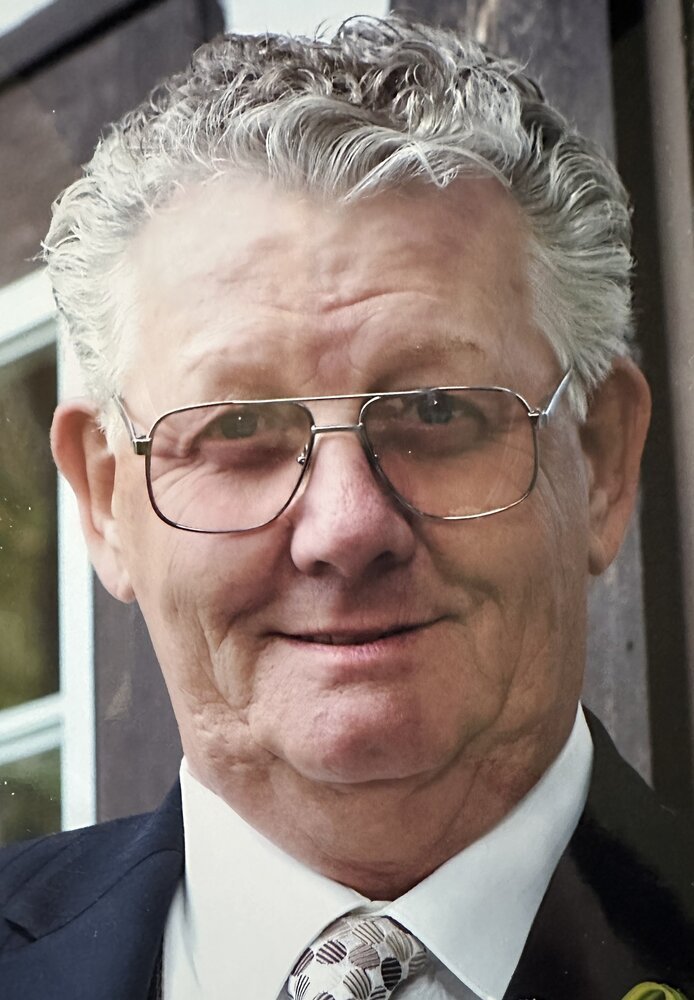 Smiling elderly man with glasses and suit.