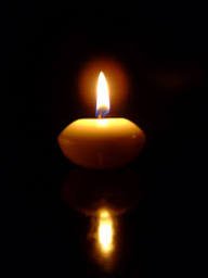 Lit candle flame in the dark with reflection