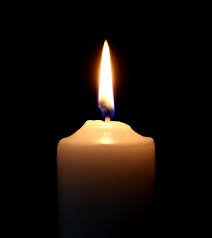Lit white candle in darkness