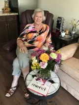 Woman seated with colorful flowers on table.