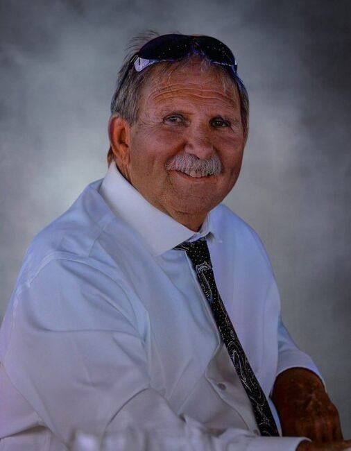Smiling man in white shirt with sunglasses.
