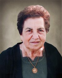 Elderly woman smiling, wearing a green top.