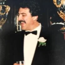Man in tuxedo with mustache holding drink