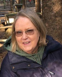 Person outdoors wearing a jacket and glasses.