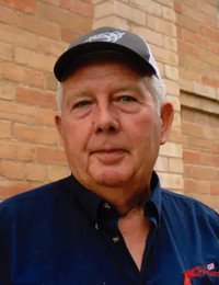 Older man with hat against brick wall