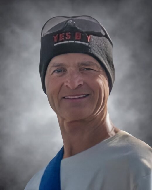 Person smiling wearing a beanie and sunglasses on head.