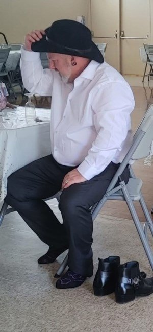 Man in hat sitting on chair indoors.