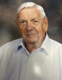 Elderly man smiling in a light-colored shirt.