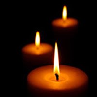 Three glowing candles in the dark.