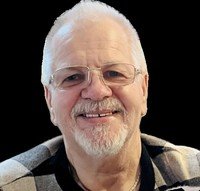 Smiling elderly man with glasses and beard.