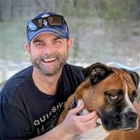 Man smiling with his dog outdoors.