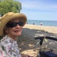 Elderly woman in sun hat enjoying a beach day.