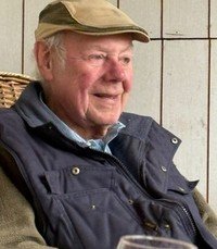 Elderly man sitting with a content smile.