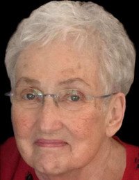 Elderly woman with short white hair and glasses.