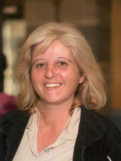 Smiling person with blonde hair indoors.