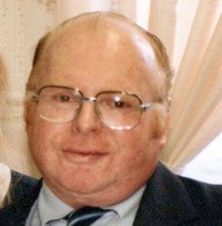 Man in suit and glasses smiling indoors.