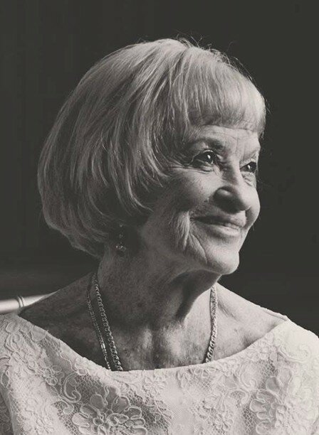 Elderly woman smiling, black and white portrait.
