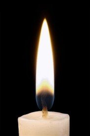 Lit candle with bright flame on black background.