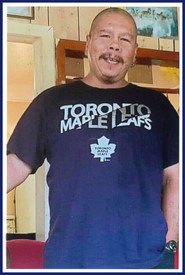 Man wearing Toronto Maple Leafs t-shirt, indoors.