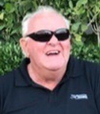 Man smiling with sunglasses outdoors.