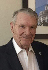 Elderly man in suit smiling at camera.