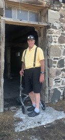 Person in vintage attire at historic stone building entrance.