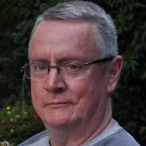 Person with glasses outside near bushes