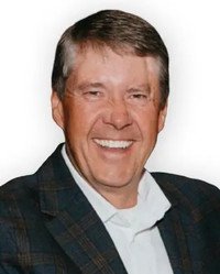 Smiling man in plaid jacket and white shirt.