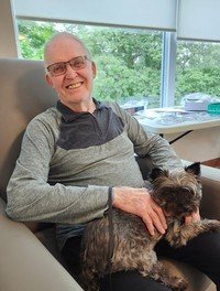 Smiling man with small dog in armchair