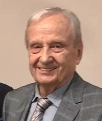 Elderly man smiling in a suit and tie.