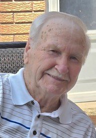 Elderly man smiling outdoors in striped shirt.