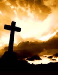 Silhouette of cross against dramatic sunset sky.