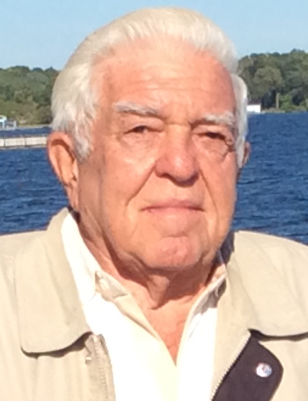 Elderly man by a lake on a sunny day.