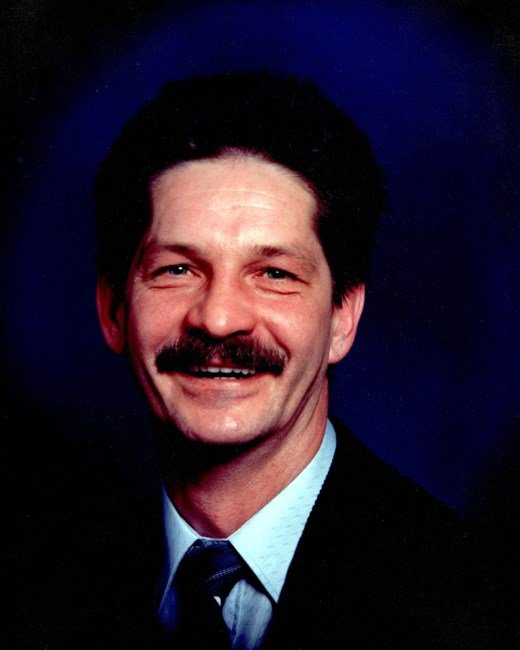 Smiling man with mustache in formal attire.