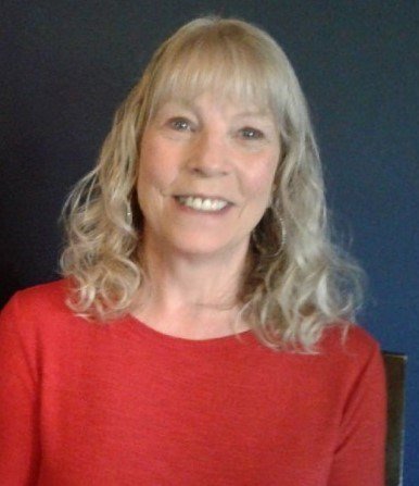 Smiling person with curly hair in red shirt.