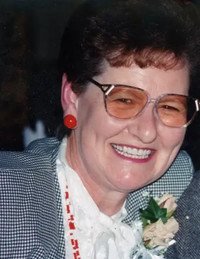 Smiling woman with glasses and red earrings.
