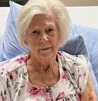 Elderly woman smiling in a floral shirt.
